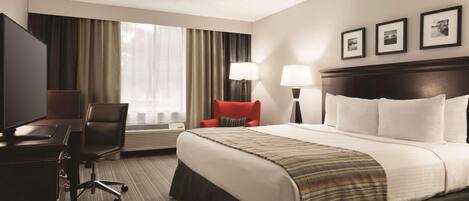 Una habitación de hotel con cama, escritorio, silla y dos lámparas.