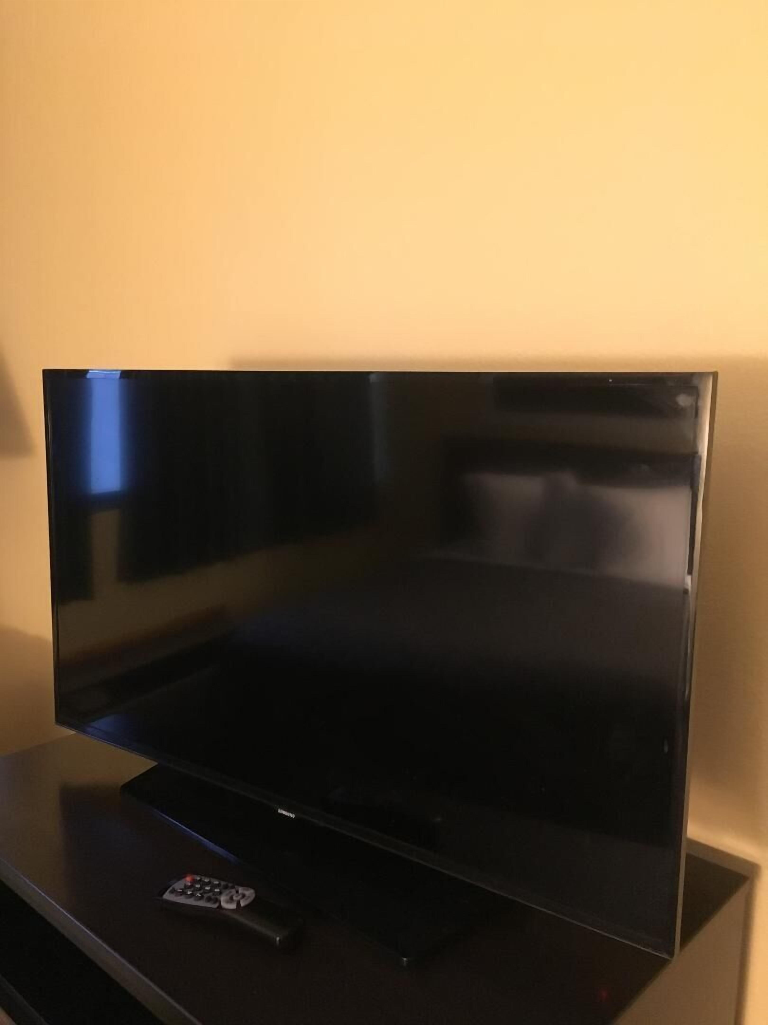 Un televisor de pantalla plana sobre un soporte negro en una habitación de hotel.