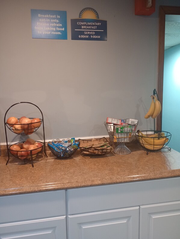 Un buffet de petit-déjeuner avec des fruits, du pain et des céréales.
