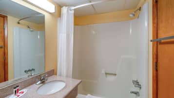 A bathroom with a sink, mirror, shower, and towel rack.