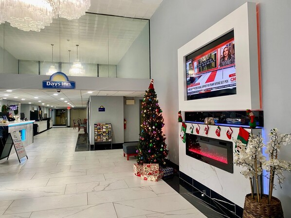 A hotel lobby with a reception desk, a Christmas tree, and a TV displaying news. - Days Inn by Wyndham Scranton PA (Scranton)