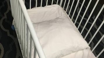 Un berceau en métal blanc, avec un matelas et un oreiller.