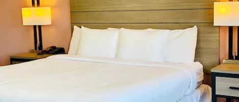 A hotel room with a large bed, two bedside tables, and two wall-mounted lamps.