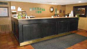 En receptionsdisk med en skylt som visar texten ”Emerald Inn” och en klocka på väggen.
