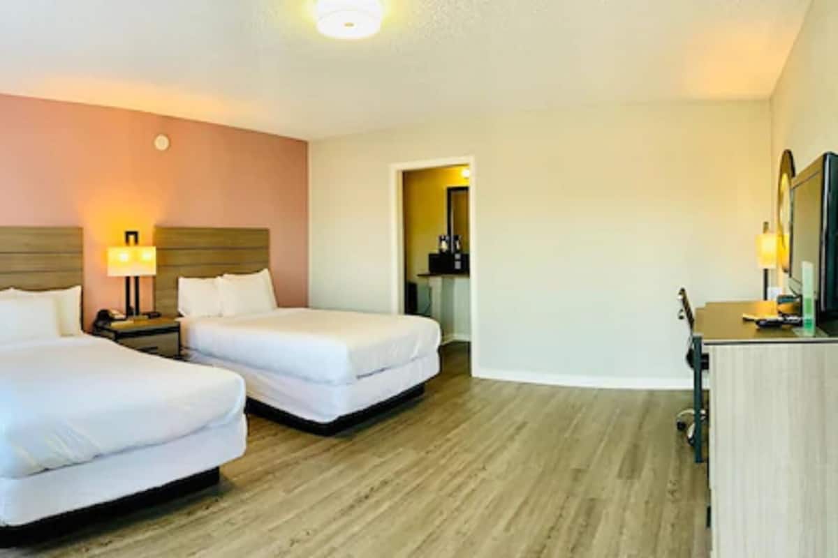 Une chambre d’hôtel avec deux lits, un bureau et un miroir.