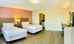 A hotel room with two beds, a desk, and a mirror.