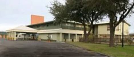 A two-story building with a flat roof and a large orange structure on the roof. There are trees in front of the building.