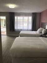 Habitación de hotel con dos camas, una ventana con cortinas, una lámpara en el techo y vistas al exterior.