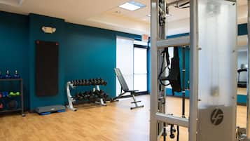 A gym with exercise equipment, a wall-mounted dumbbell rack, and a bench.