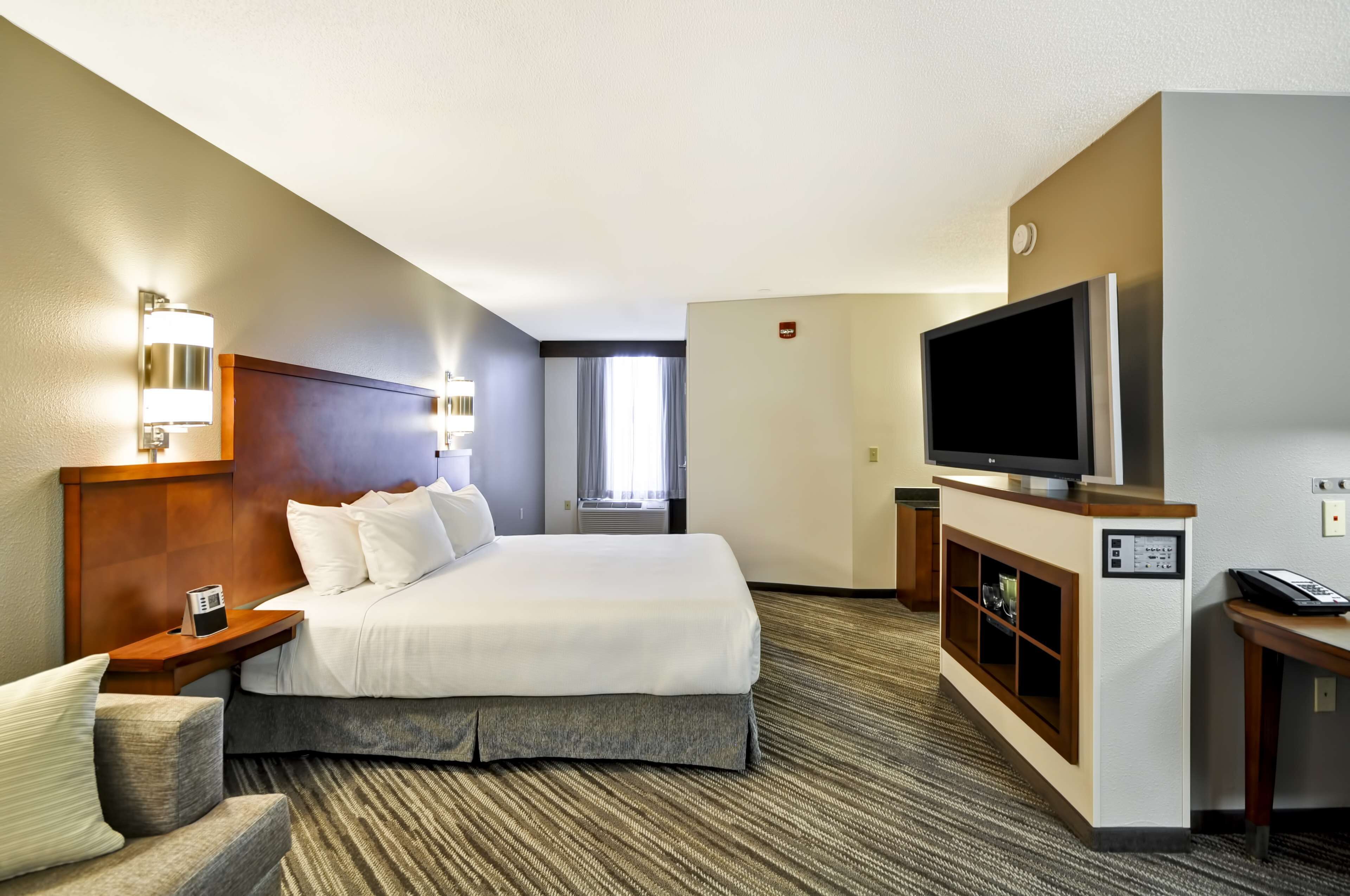 Una habitación de hotel con una cama grande, televisión, escritorio y una silla.