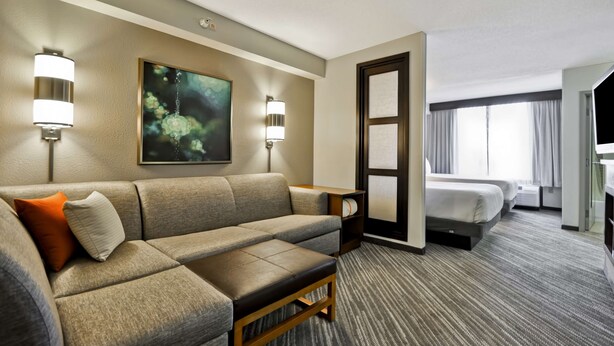 Une chambre d’hôtel avec un canapé, un lit, un tableau au mur et une lampe.