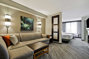 Habitación de hotel con sofá, cama, un cuadro en la pared y una lámpara.