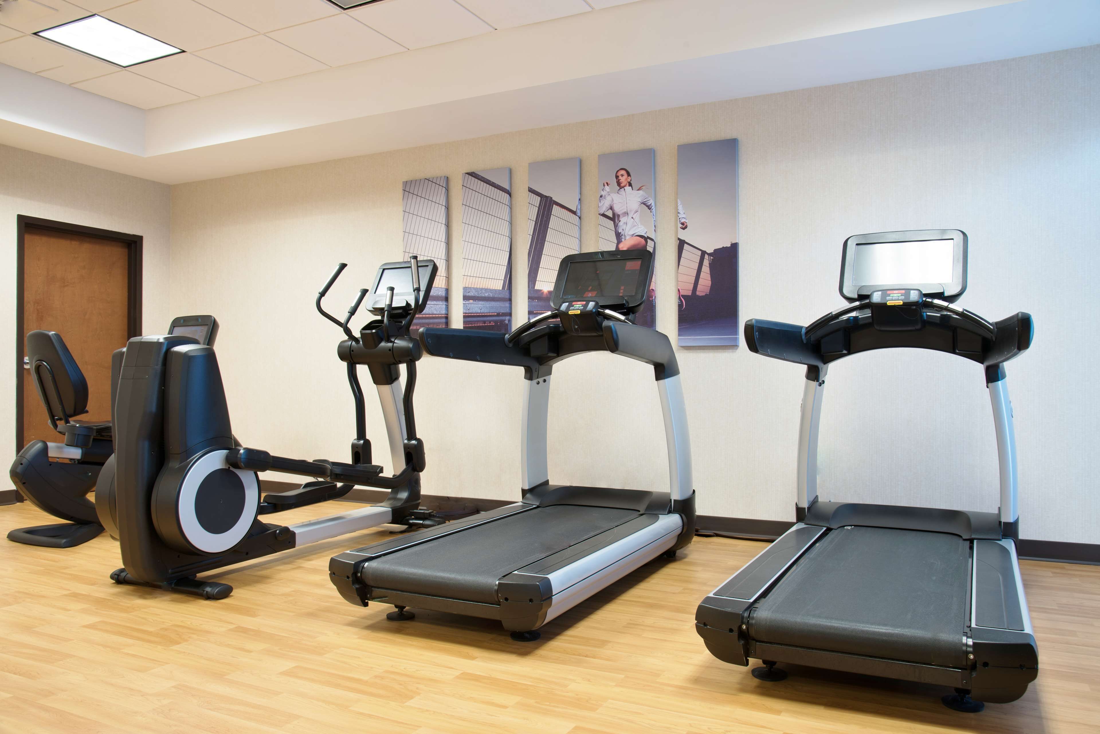 Un gimnasio con tres cintas de correr, una bicicleta estática y una máquina de remo.