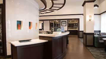 A hotel lobby with a reception desk, seating area, and a display of amenities.