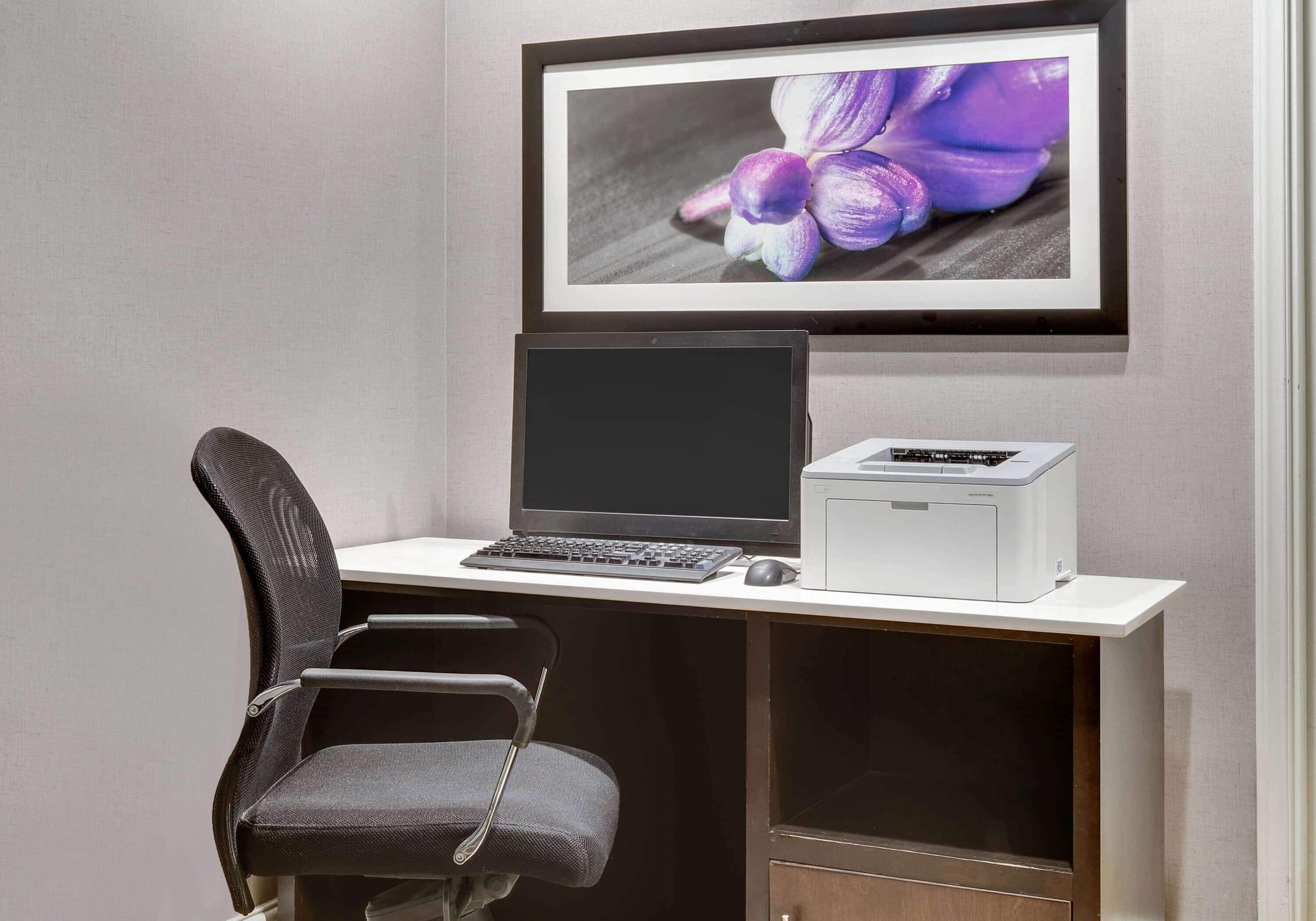 Ein Arbeitsplatz mit Computer, Drucker und Stuhl.