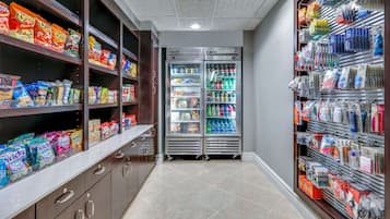 Una tienda de comestibles con estantes llenos de bocadillos y bebidas, una sección refrigerada y una exhibición de artículos de tocador.
