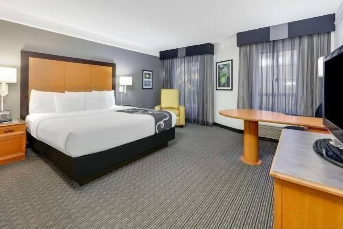 A hotel room with a bed, a desk, a chair, and a television.