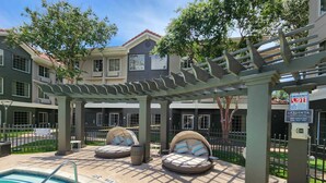 Et poolområde med to udendørs siddeområder, en pergola og et skilt for La Quinta Inn & Suites.