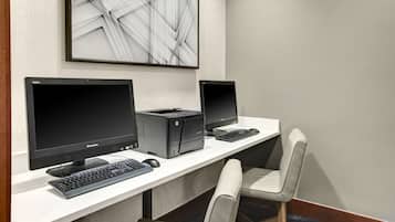 A modern office setup with two monitors, a desktop computer, and a keyboard on a white desk.