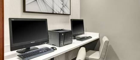 A modern office setup with two monitors, a desktop computer, and a keyboard on a white desk.