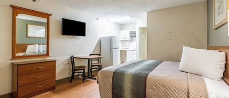 Habitación de hotel con cama, escritorio, silla, cómoda, televisor y microondas.