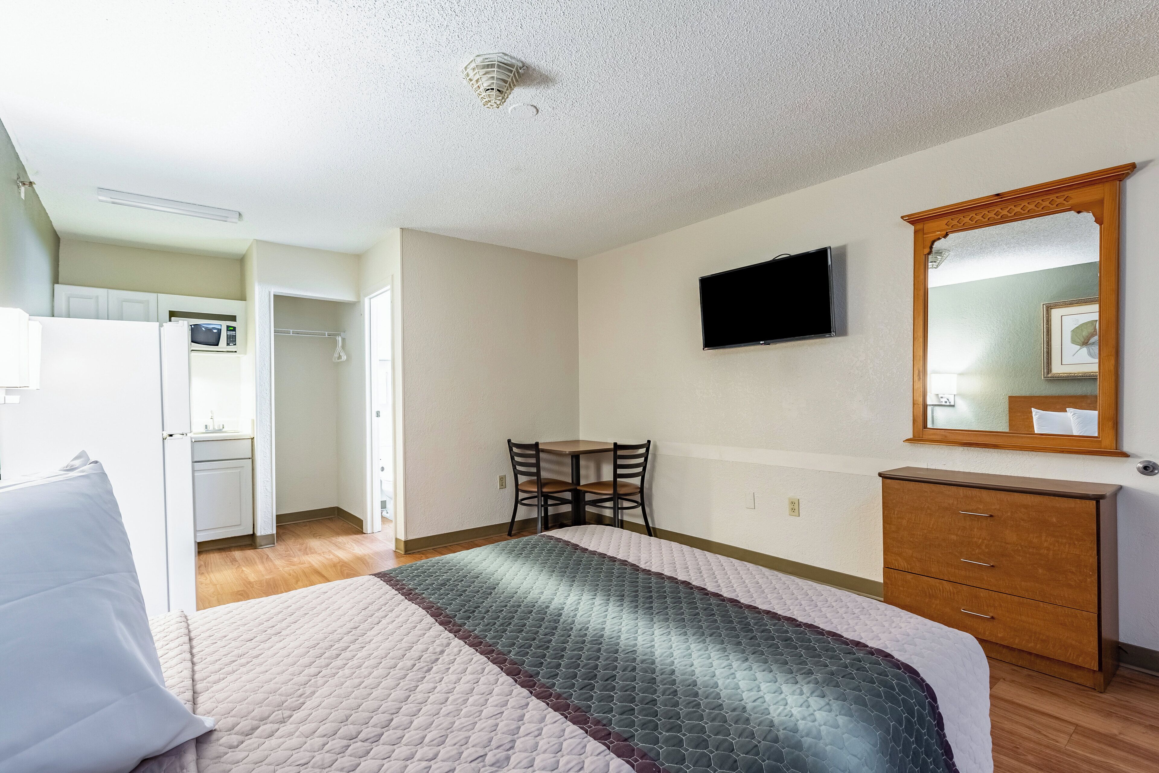 A hotel room with a bed, a desk, a chair, a television, and a wardrobe.