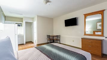 A hotel room with a bed, a desk, a chair, a television, and a wardrobe.