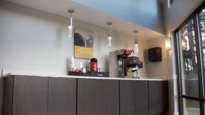 A modern reception area with a marble floor, a coffee machine, and a Bunn coffee maker. - Motel 6 Suwanee, GA - Gwinnett Center (Suwanee)