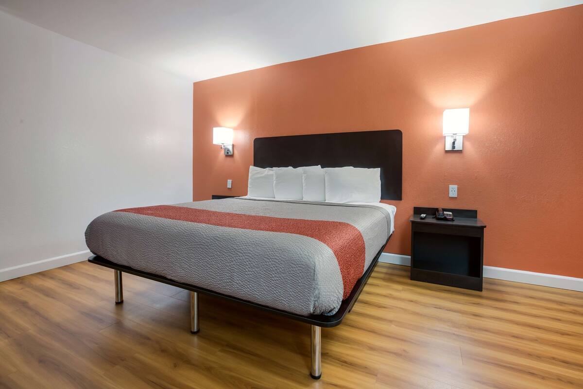 A neatly arranged hotel room with a bed, two bedside tables, and a wall-mounted light fixture.