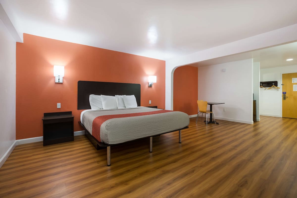 A hotel room with a bed, bedside tables, a small table with chairs, and a door leading to a bathroom.