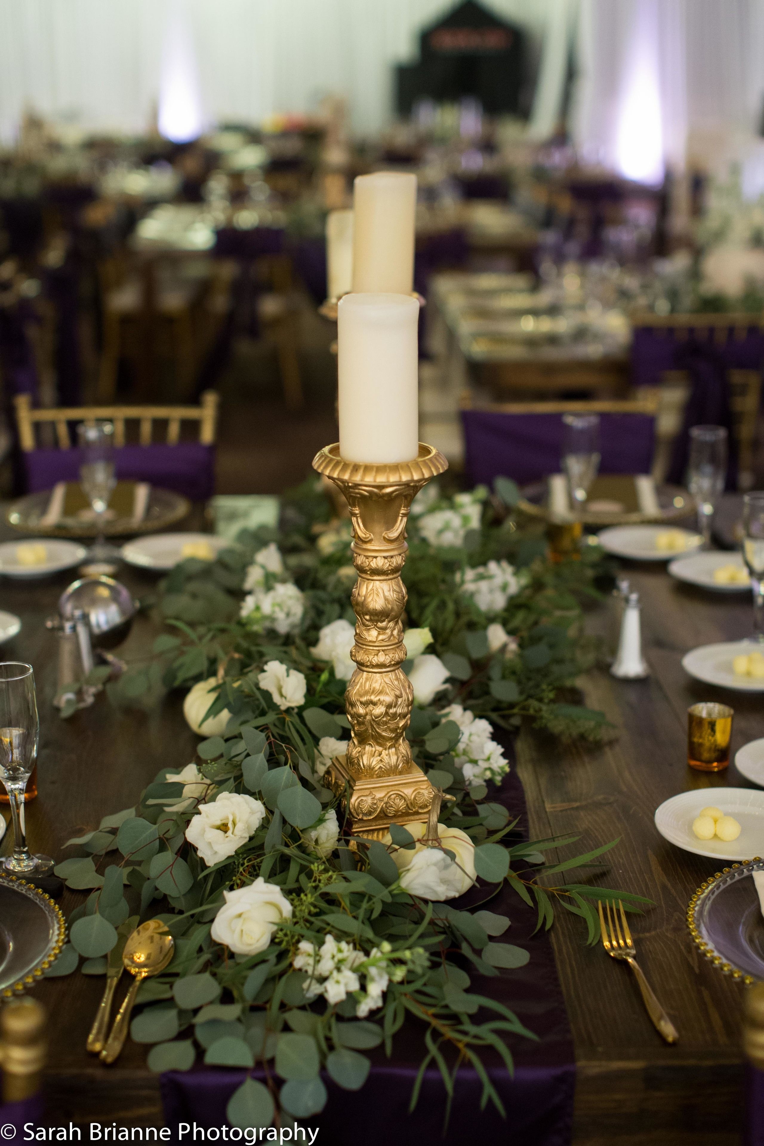 A table set for a formal event with a centerpiece of flowers and a tall candle.