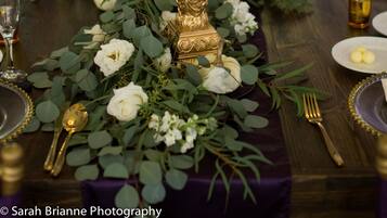 A table set for a formal event with a centerpiece of flowers and a tall candle.
