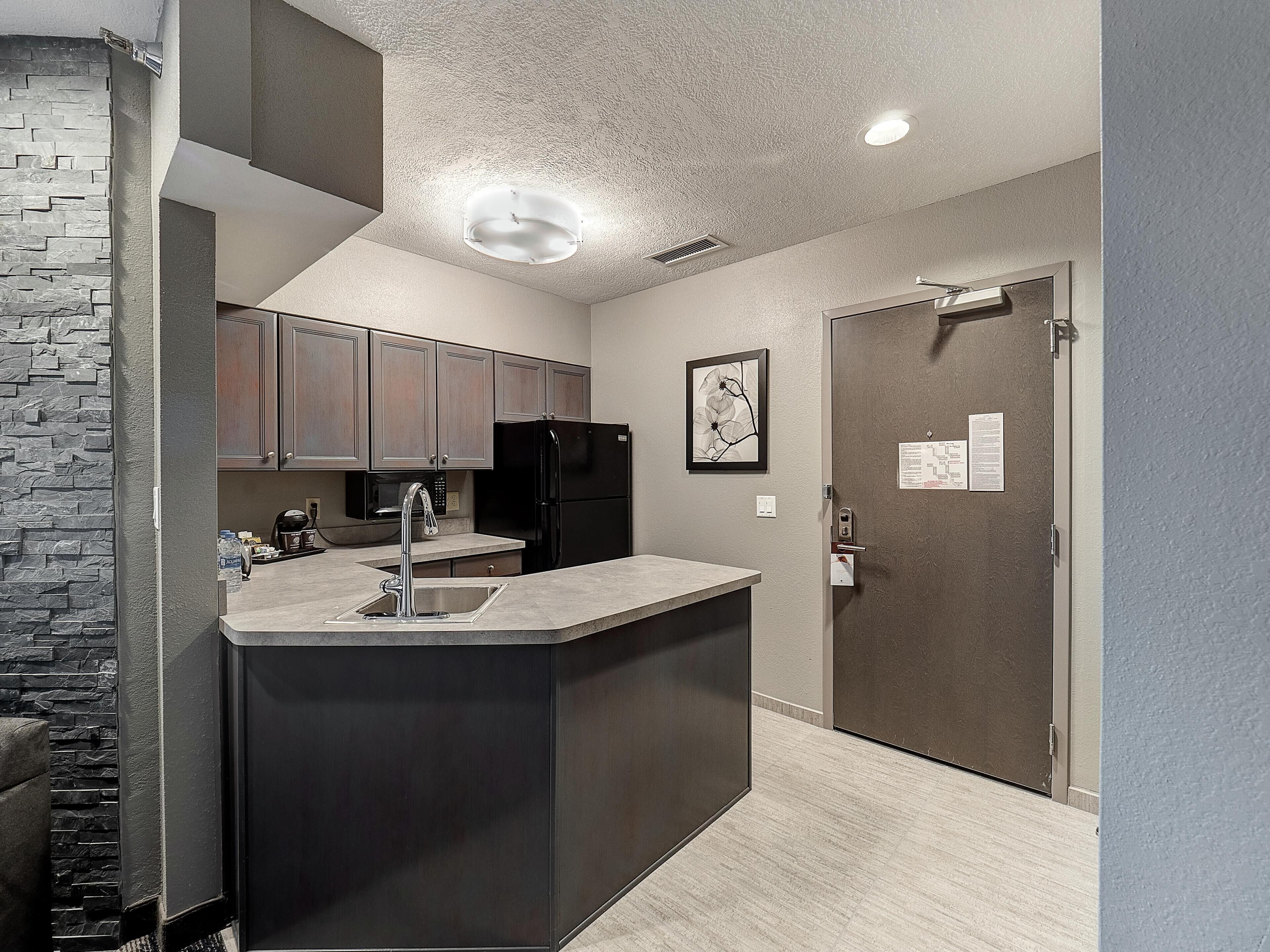 A modern kitchen with a built-in island, stainless steel appliances, and a stone accent wall.