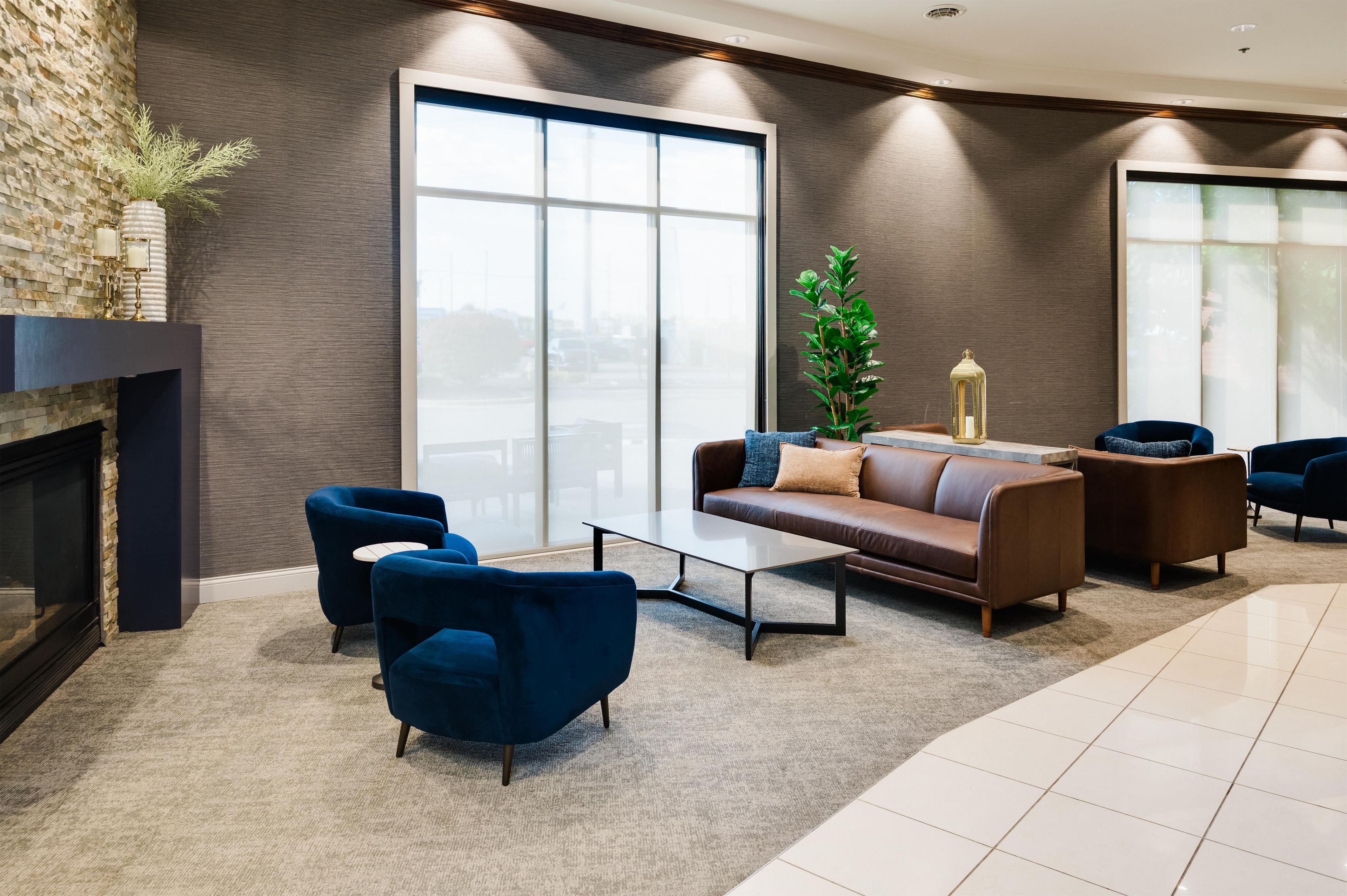 A modern lounge area with a fireplace, seating, and large windows.