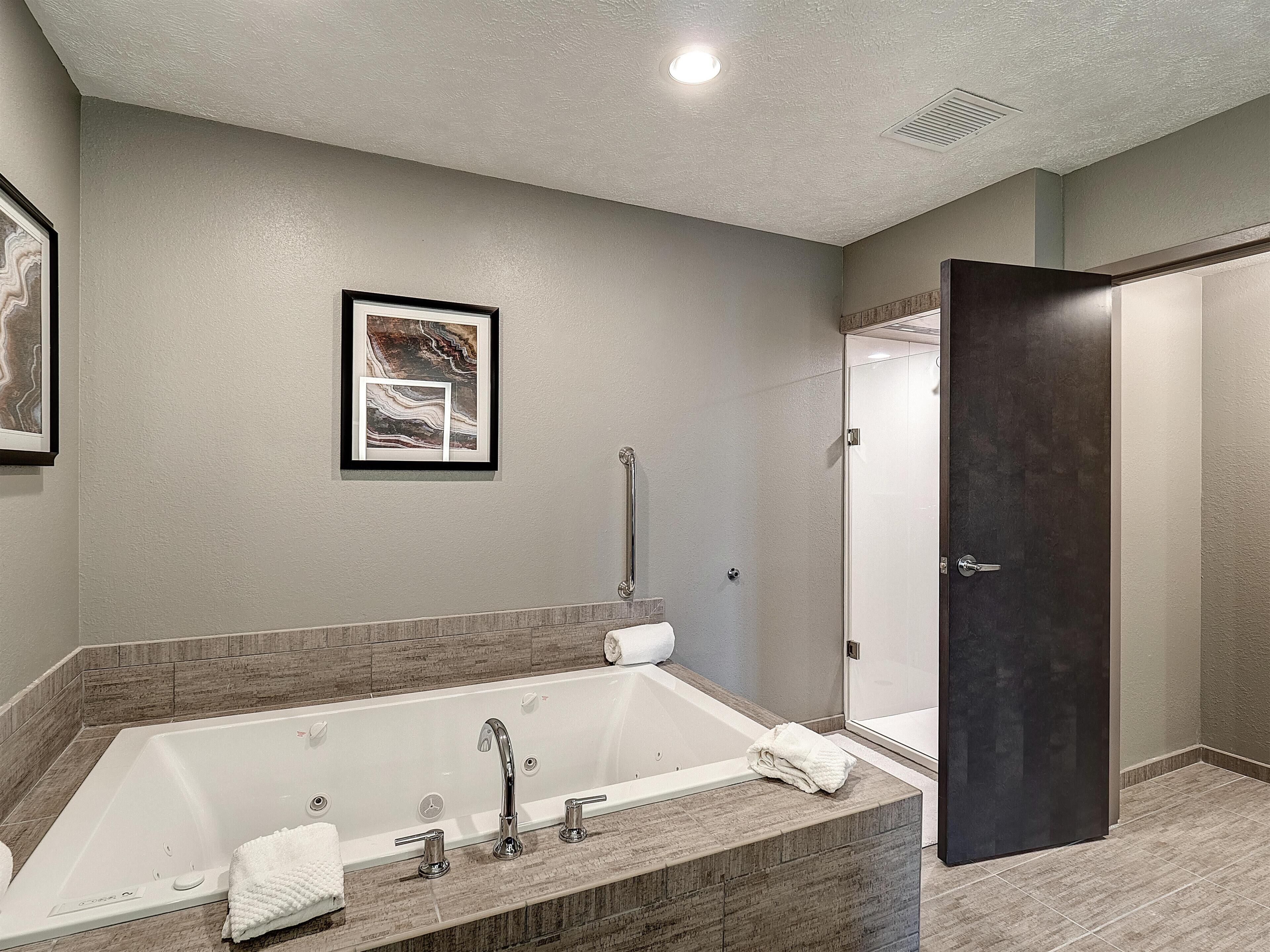 A bathroom with a bathtub, a shower, and a door.