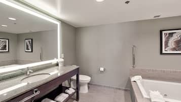 Une salle de bain moderne avec un grand miroir, une baignoire, des toilettes et un meuble-lavabo.