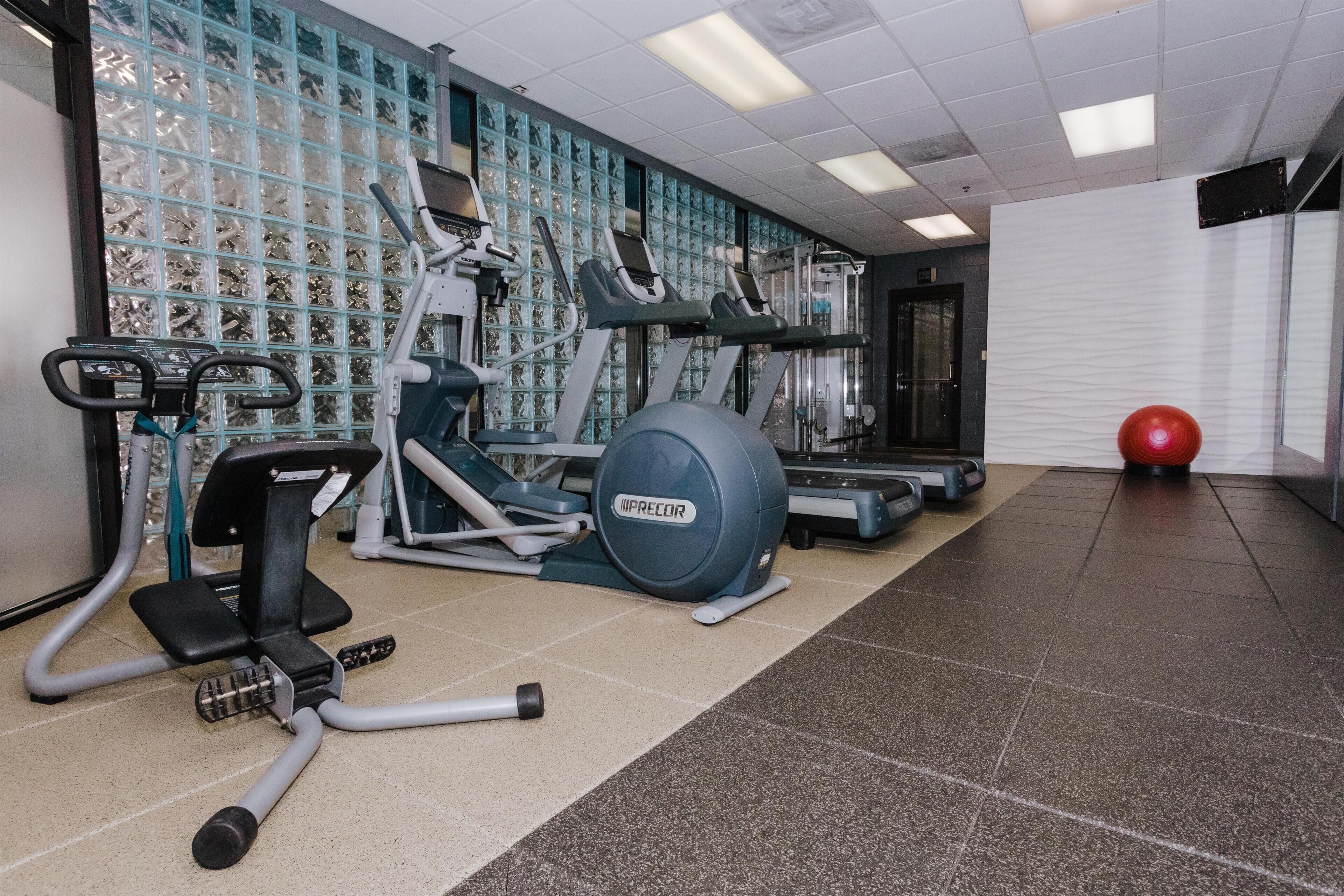 A gym with exercise equipment, a red exercise ball, and a patterned wall.