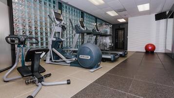 A gym with exercise equipment, a red exercise ball, and a patterned wall.