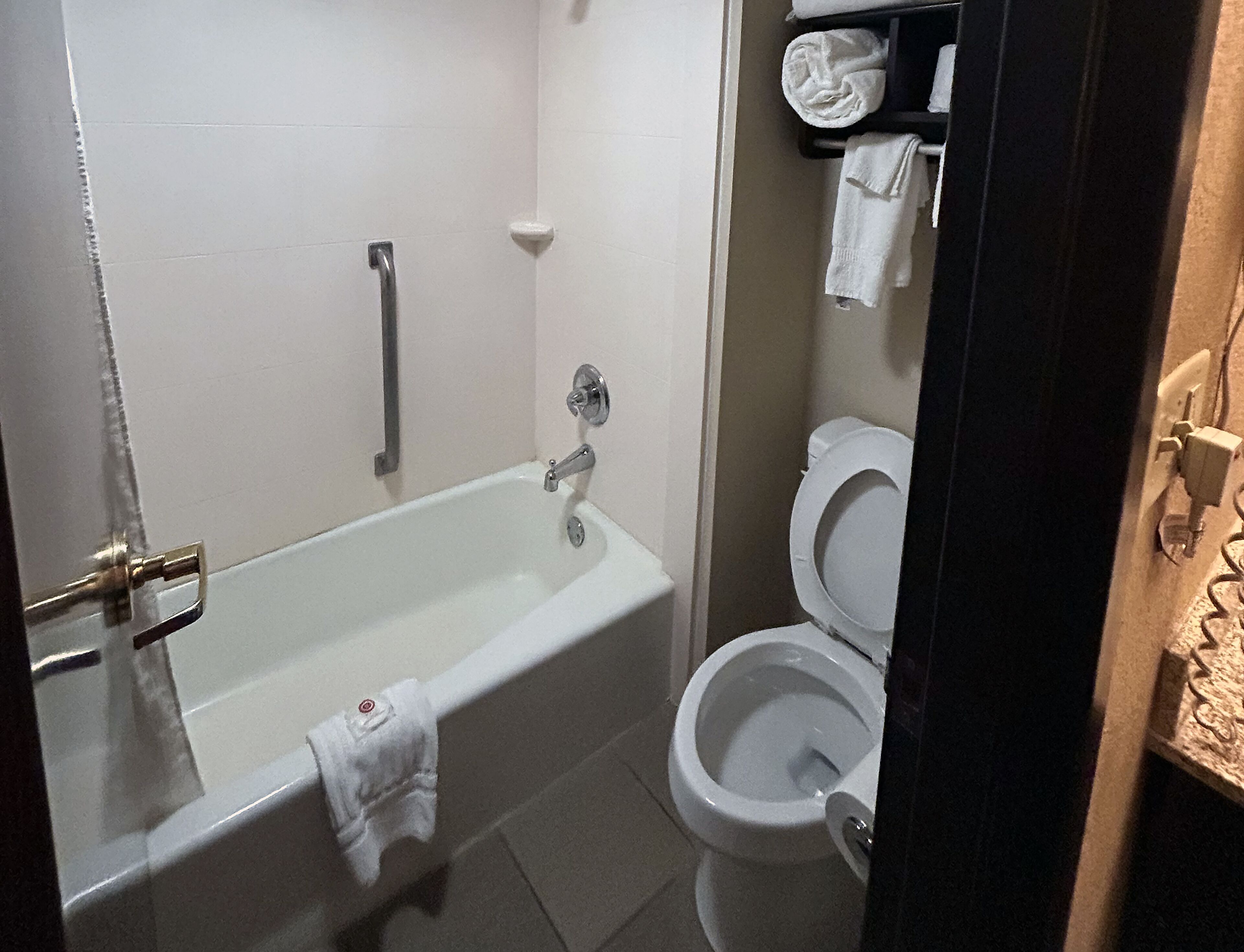 A bathroom with a bathtub, toilet, and a towel rack.