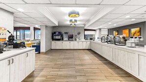 A modern kitchen with a long counter, built-in appliances, and a wooden floor. - Comfort Inn & Suites Evansville Airport (Evansville)