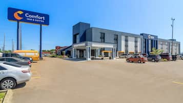 Un hotel Comfort Inn & Suites dal design moderno, con un ampio parcheggio e un cielo azzurro.