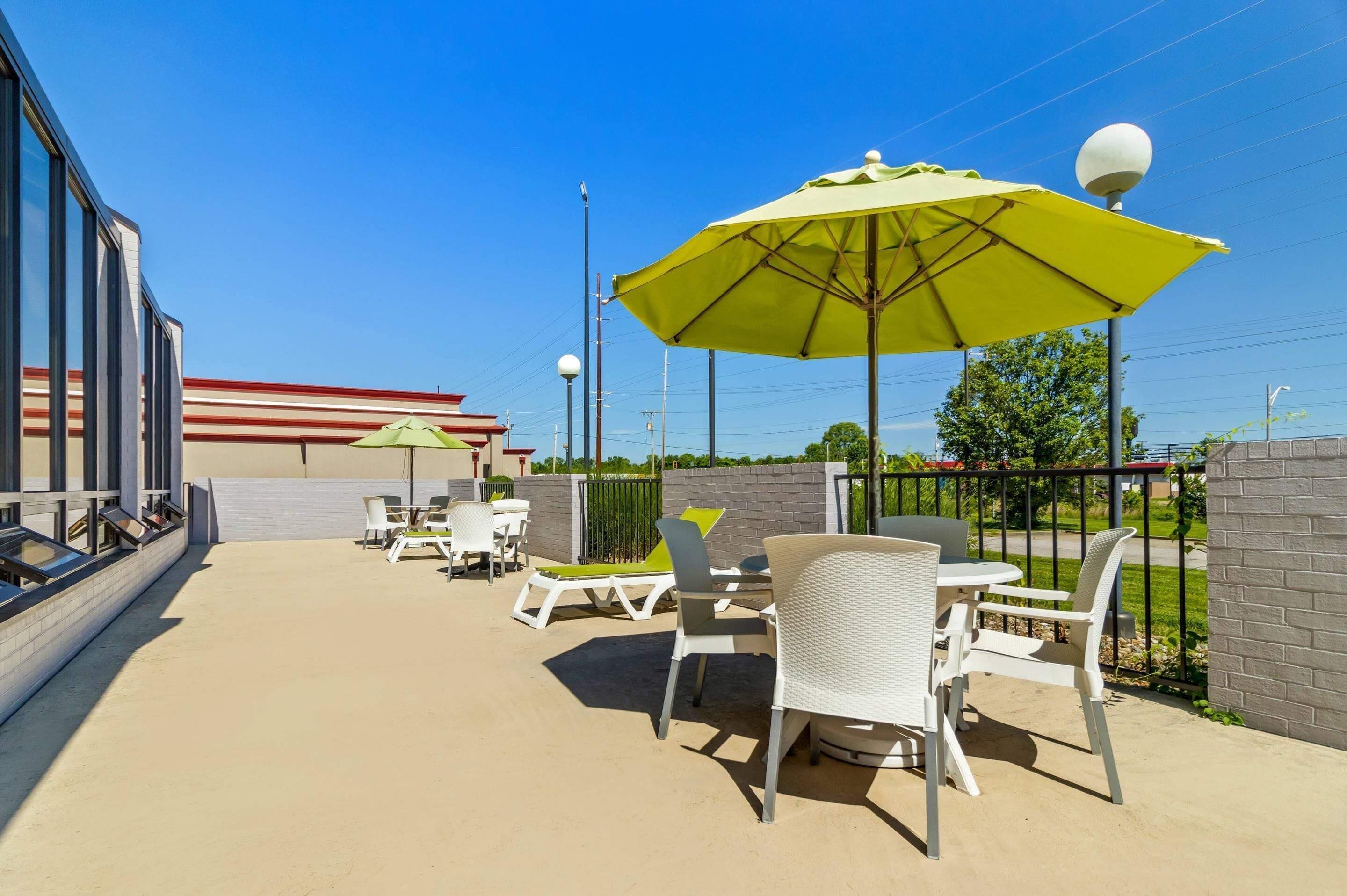 An outdoor patio area with tables and chairs, a yellow umbrella, and a building in the background.