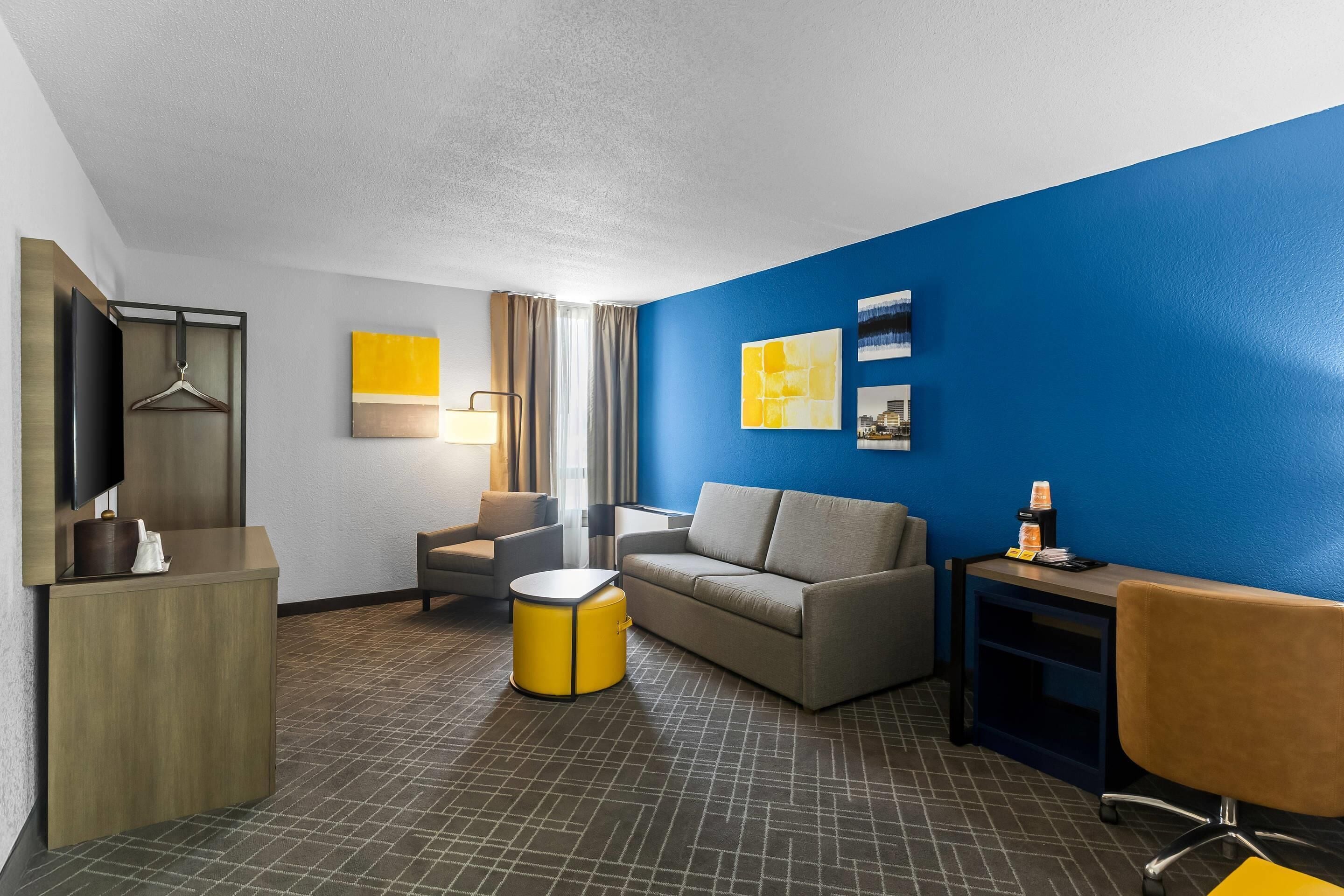 Habitación de hotel con sofá, sillón y una mesita de noche con lámpara.