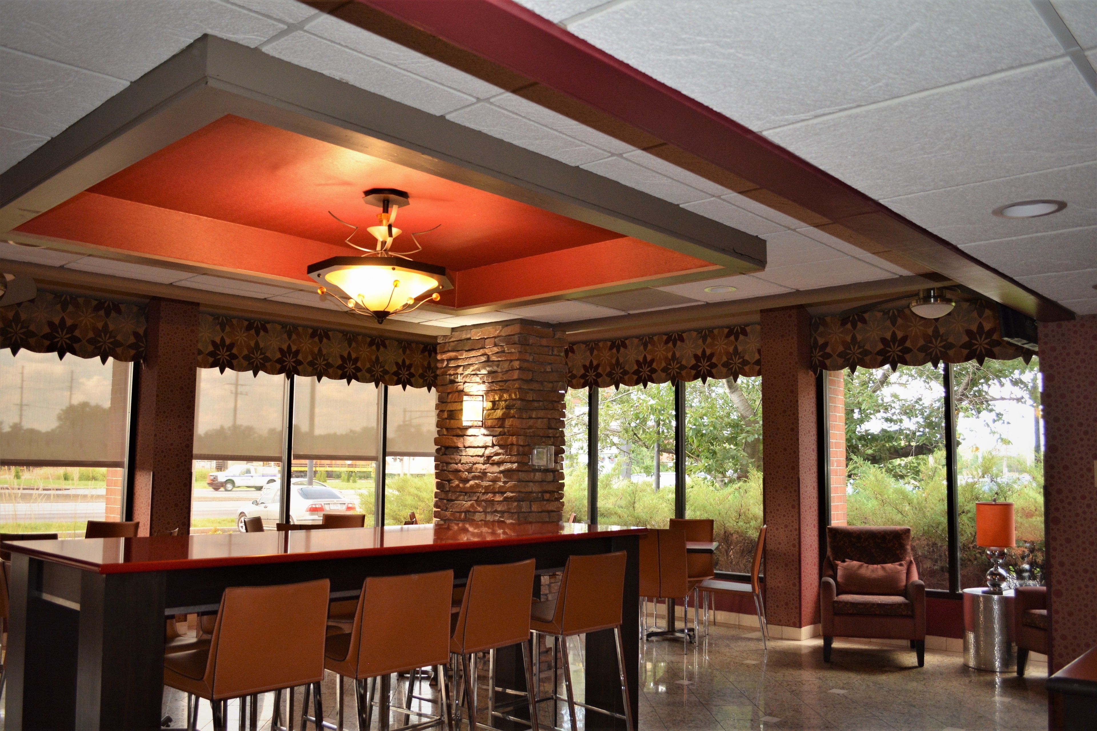 A restaurant with a bar area, large windows, and a stone pillar.