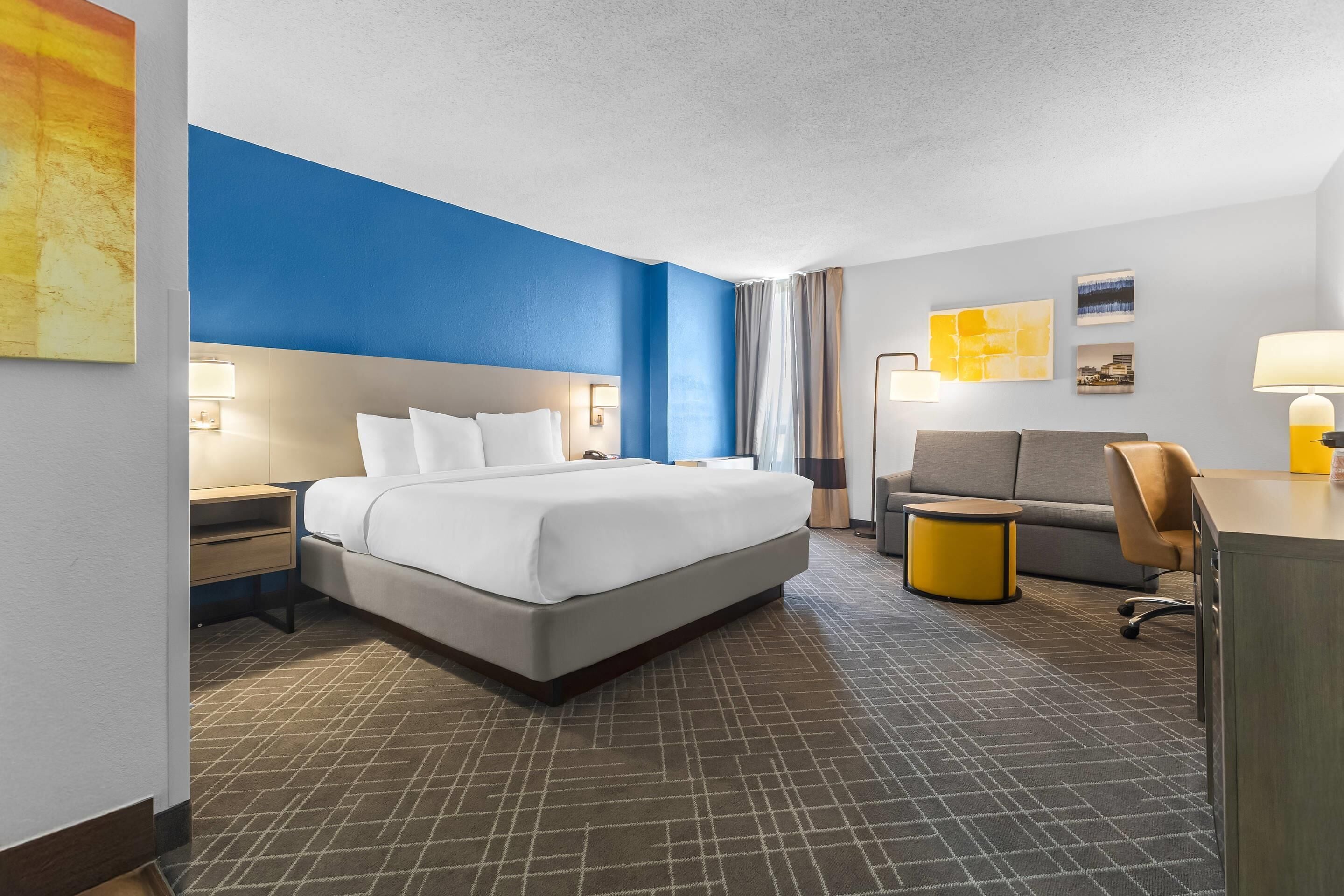 Una habitación de hotel con una cama grande, un escritorio, un sofá y una silla.