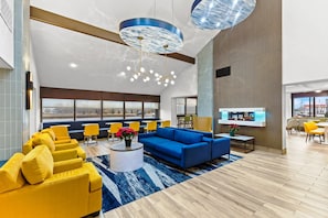 A modern lobby with seating areas, a coffee table with flowers, and a large window with a view. - Comfort Inn & Suites Evansville Airport (Evansville)