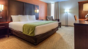 Una habitación de hotel con una cama grande, un escritorio, una silla y una lámpara.