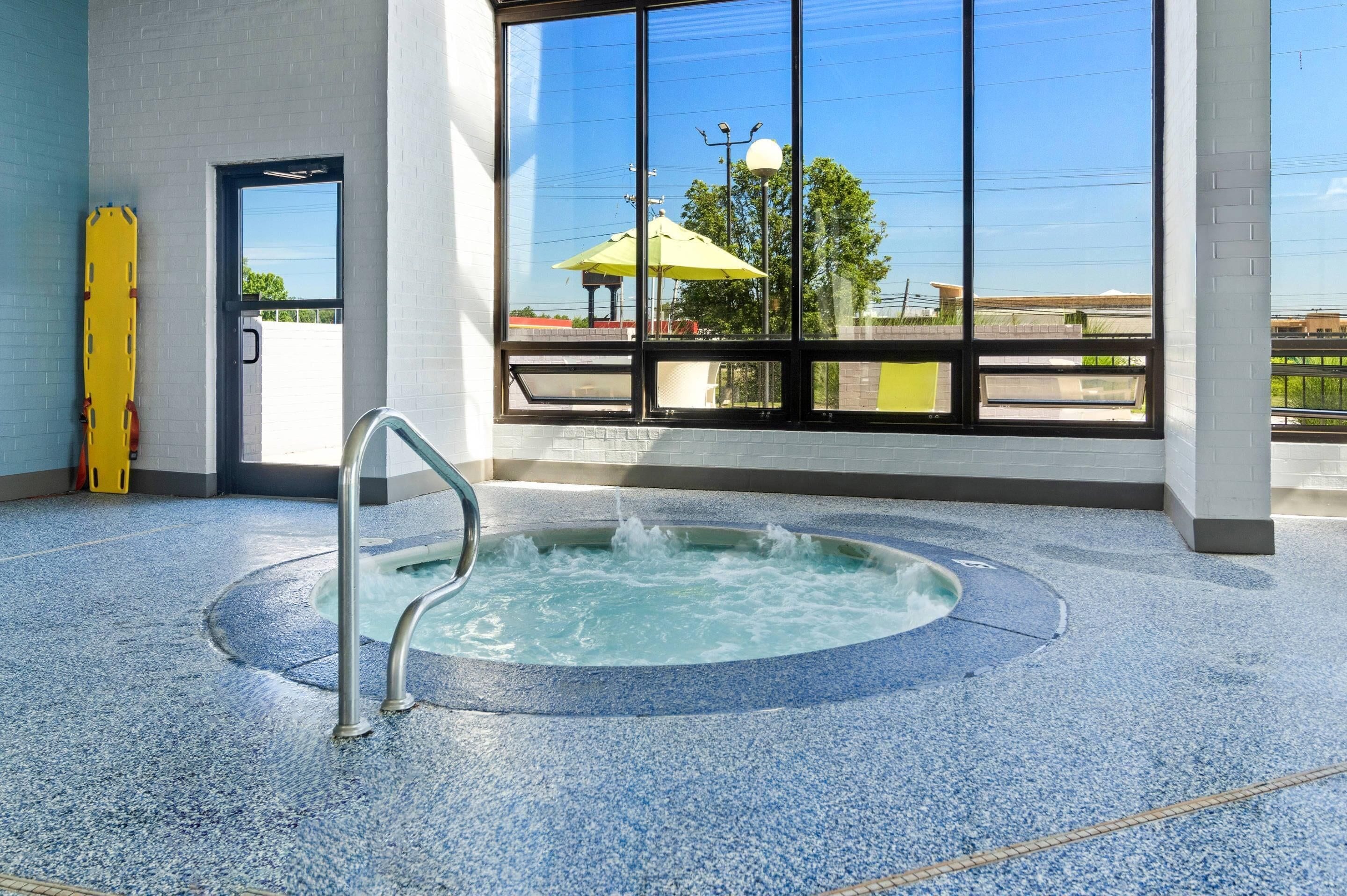A hot tub in a room with large windows, a door, and a yellow object on the floor.
