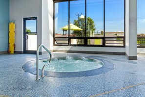 A hot tub in a room with large windows, a door, and a yellow object on the floor. - Comfort Inn & Suites Evansville Airport (Evansville)