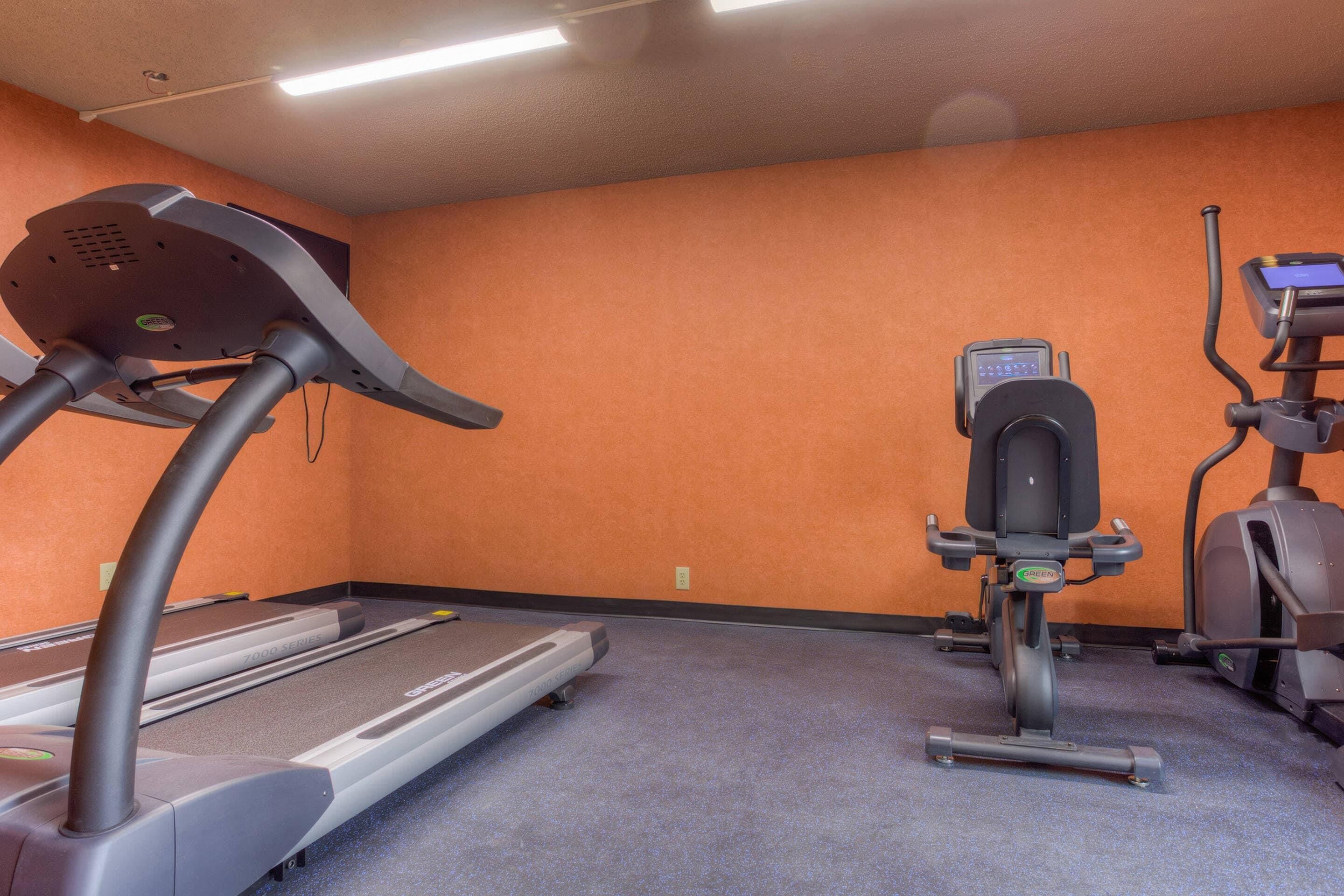 A fitness room with a treadmill, elliptical, and stationary bike.